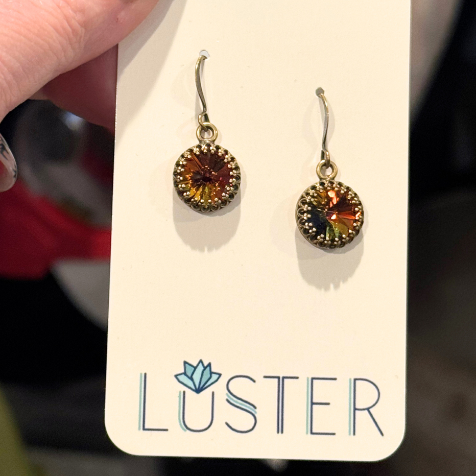 Round earrings on a Luster branded card held by a hand.