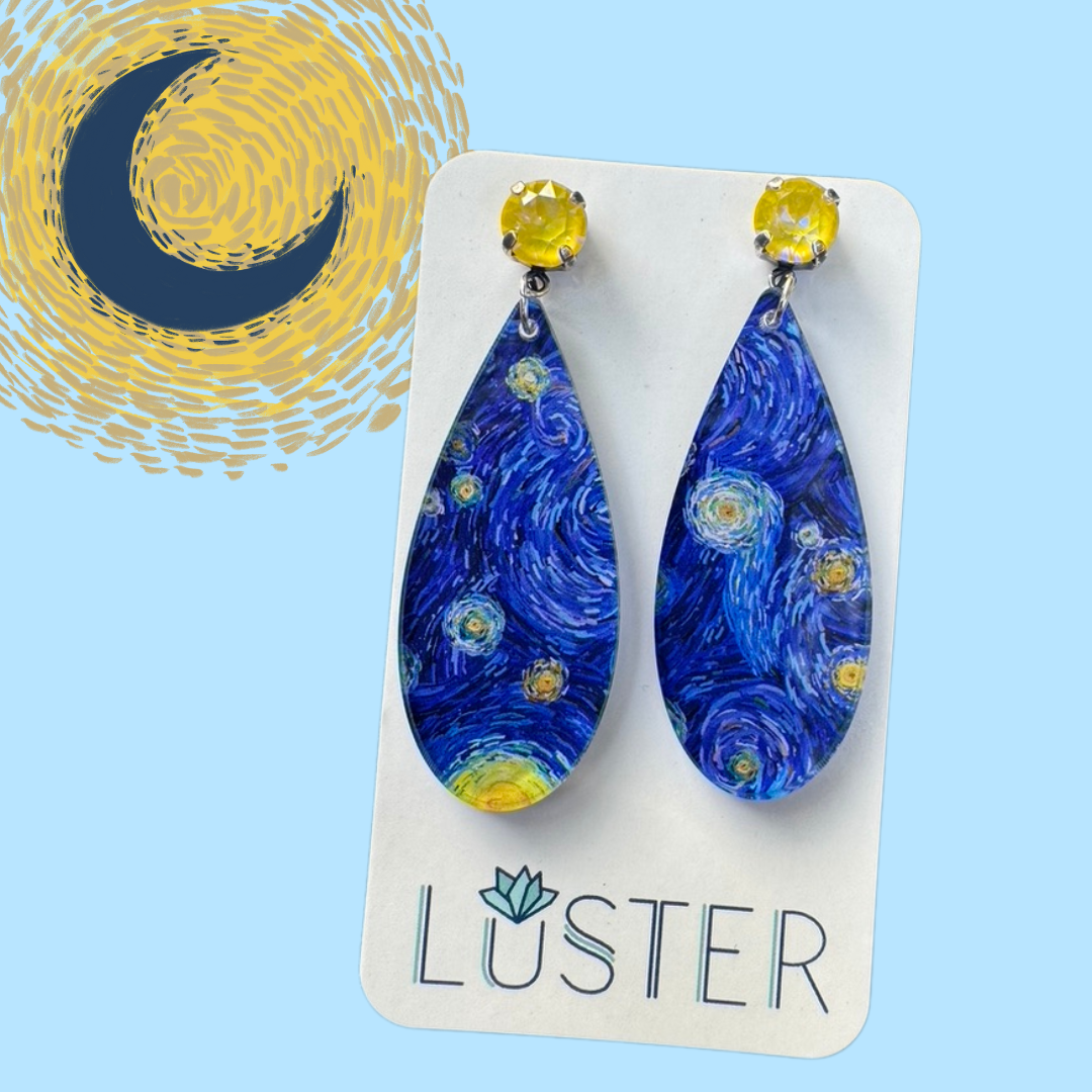 Pair of blue teardrop earrings with yellow accents on a Luster branded card against a blue background with a moon design.