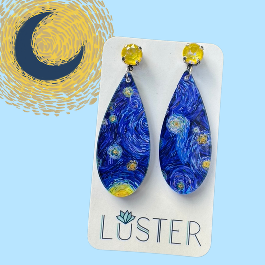 Pair of blue teardrop earrings with yellow accents on a Luster branded card against a blue background with a moon design.