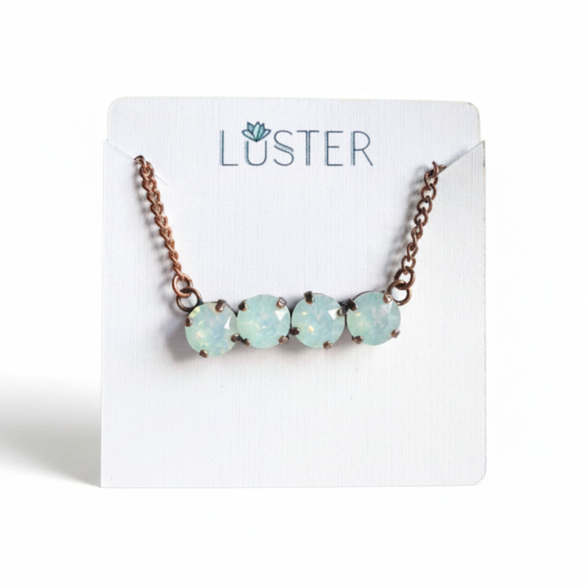 Necklace with milky white crystals with copper chain on a 'Luster' branded card.