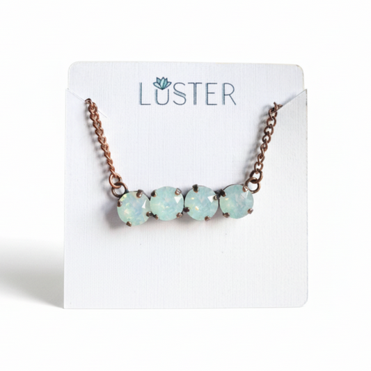 Necklace with milky white crystals with copper chain on a 'Luster' branded card.
