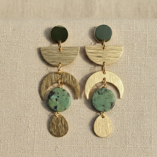 brass celestial earrings with green stone on a linen background