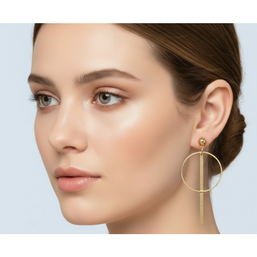 Close-up of a woman wearing gold hoop earrings against a light blue background
