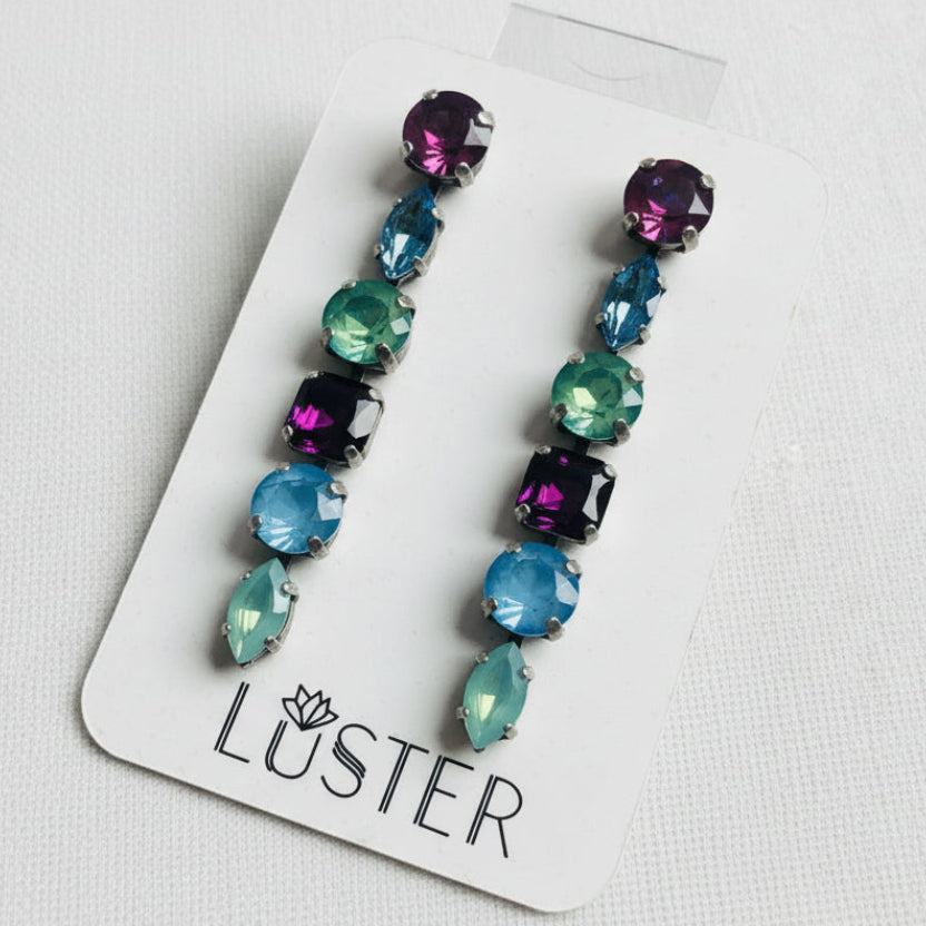 Multicolored crystal earrings on a Luster branded card against a white background