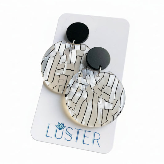 Pair of earrings on a Luster branded card against a white background