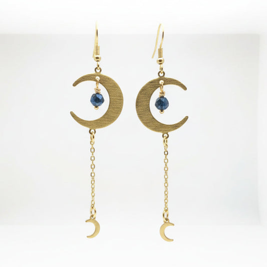 Pair of gold earrings with crescent moon and chain design on a white background