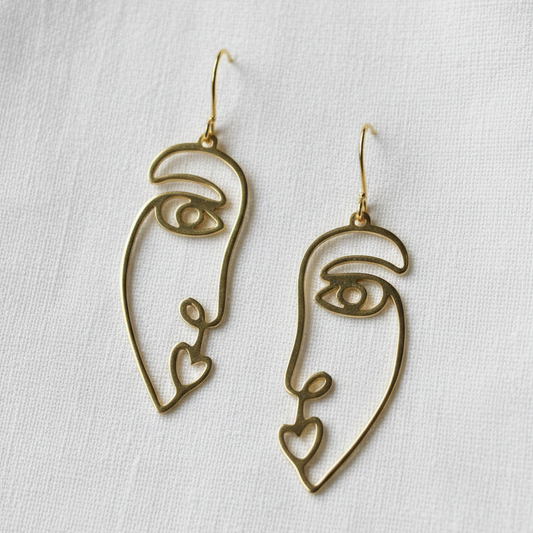 Gold abstract face earrings on a natural background